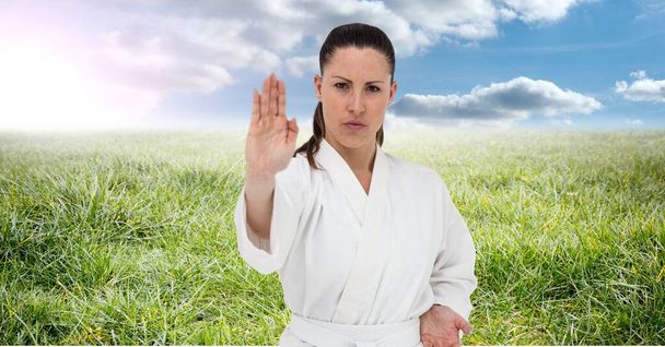 Digital composite image of portrait of caucasian female marital artist against grass and blue sky. sports competition and tournament concept - Photo, Image