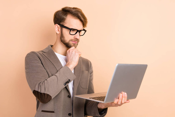 Profile photo of serious nice blond hair man hold laptop wear spectacles grey jacket isolated on beige background - Valokuva, kuva