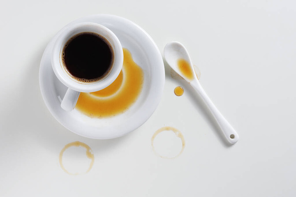 Direkt über dem Blick auf verschüttete Tasse Kaffee auf weißem Tisch - Foto, Bild