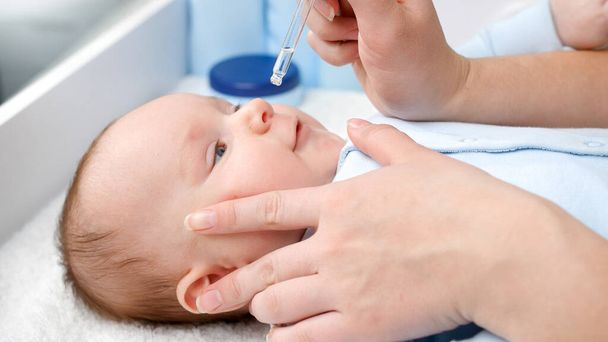 Curar al bebé con secreción nasal usando medicamentos en gotitas de secreción nasal. Concepto de salud infantil, cuidado del bebé y atención médica. - Foto, imagen