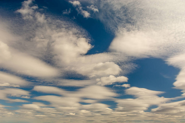 Fehér bolyhos felhők a kék ég hátterében. A Nap megvilágítása hangsúlyozza a kifogástalanságukat és súlytalanságukat. Háttérkép. Üres design és kreatív - Fotó, kép