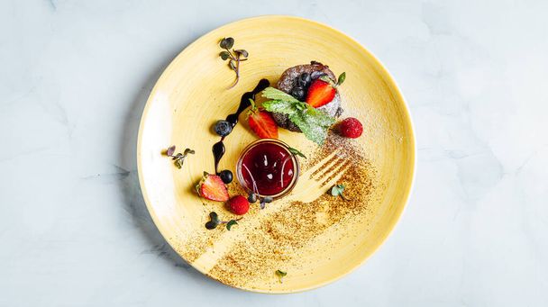 Closeup de um queque de chocolate com uma tigela de geléia de morango na placa - Foto, Imagem