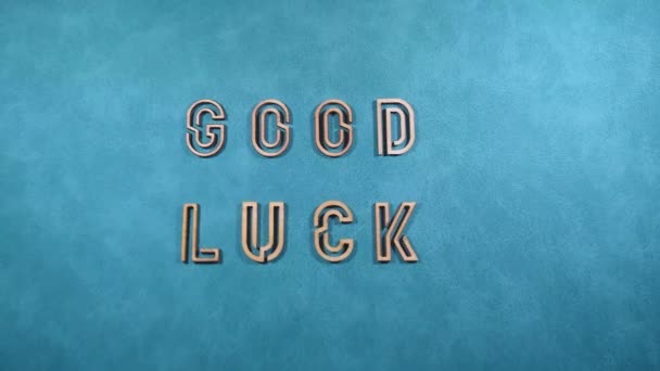 la phrase Je vous souhaite bonne chance en lettres de bois sur une surface bleue gros plan - Séquence, vidéo