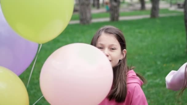 sladká brunetka dospívající dívka v růžové mikině baví s horkovzdušnými balónky. Veselé letní dny, prázdniny, prázdniny. zpomalený pohyb. - Záběry, video