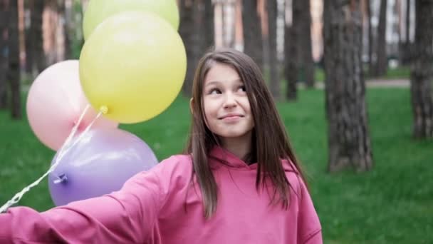 sweet brunette teenage girl in pink sweatshirt having fun with hot air balloons. happy summer days, vacation, holidays. slow motion. - Footage, Video