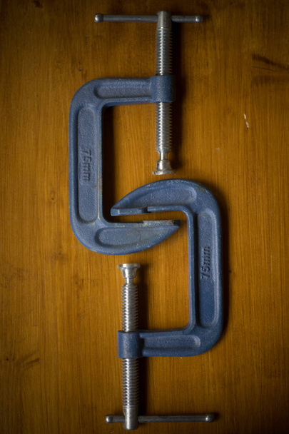 Close-up tiro de dois c-clamps em um fundo de madeira. - Foto, Imagem