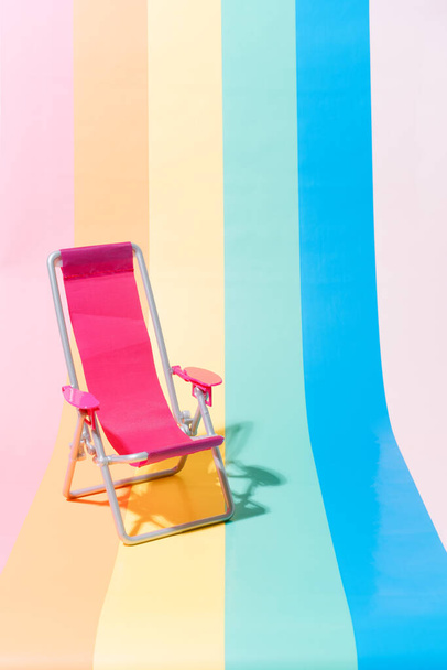 Chaise de plage rose sur fond multicolore. Voyage et concept d'été. Illustration 3d. espace de copie - Photo, image