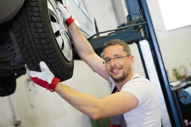 Mechanic checking wheel bearings in a car workshop  - Photo, Image