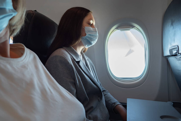 Οι επιβάτες του αεροπλάνου πετούν με ιατρικές μάσκες. - Φωτογραφία, εικόνα