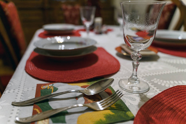 Decoración navideña festiva de la mesa. Hermosa ropa blanca y roja y servilletas, plato vacío vaso de vino cubertería. Santa Claus en un abrigo rojo - Foto, Imagen