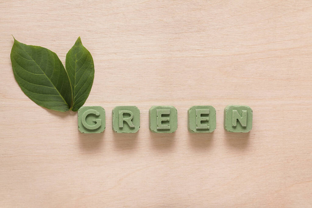 Yeşil yapraklı ahşap arkaplan ve Yeşil Blok mesajı - Fotoğraf, Görsel