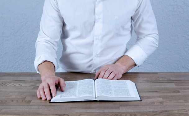 Open book Bible. A man in a shirt with a book in his hands. - Photo, Image