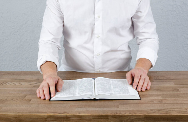 Livre ouvert Bible. Un homme en chemise avec un livre à la main. - Photo, image