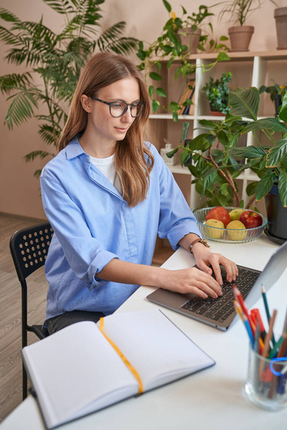 Νεαρή όμορφη γυναίκα με γυαλιά χρησιμοποιώντας το laptop - Φωτογραφία, εικόνα