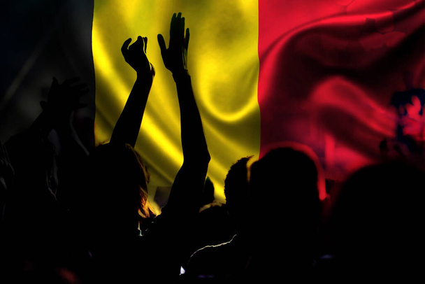 футбольные болельщики за Бельгию - толпа празднует на стадионе с поднятыми руками против бельгийского флага - Фото, изображение