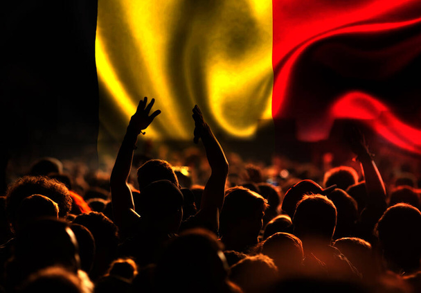 football fans supporting Belgium - crowd celebrating in stadium with raised hands against Belgium flag - Photo, Image