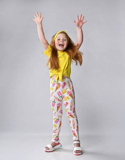 Happy overjoyed little red-haired girl child rejoicing with raised hands - Valokuva, kuva