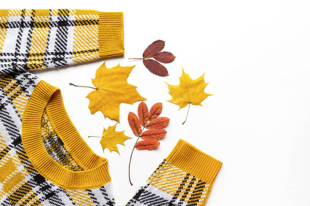 Colored fall yellow and red leaves with Orange Long Sleeve Knit Sweater. Autumn colored clothes flat lay - Zdjęcie, obraz