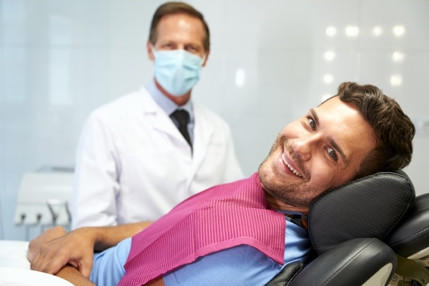 Pozytywny pacjent i jego lekarz w gabinecie dentystycznym - Zdjęcie, obraz