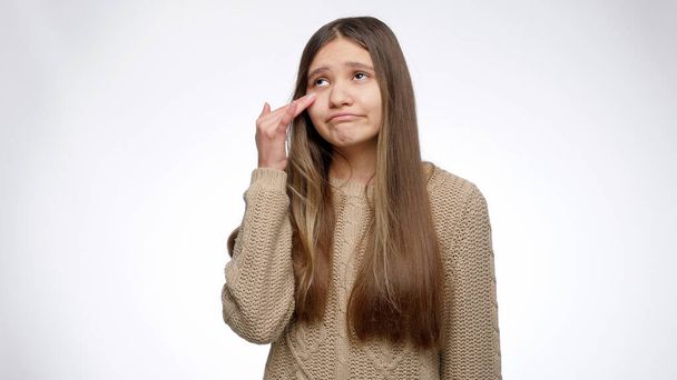 Portrét dospívající dívky otírání slz a třepání hlavou přes bílé studio pozadí. - Fotografie, Obrázek