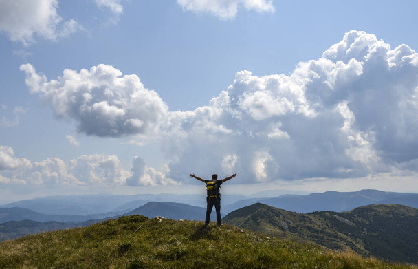 Jonge man met rugzak staan met opgeheven handen op de top van de berg en genieten van uitzicht. Sport en actief leven concept. Emotionele scène. - Foto, afbeelding