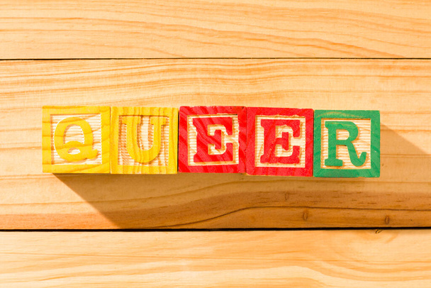 Захватывающие деревянные кубики со словом QUEER на деревянной поверхности. - Фото, изображение