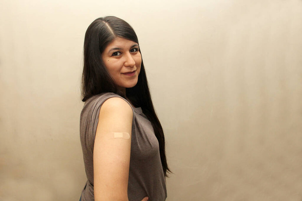 Молодая латиноамериканка 30 лет показывает свою привитую руку свободной от кобида и гриппа - Фото, изображение