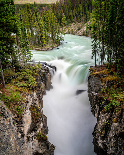 Długa ekspozycja Fotografia turkusowej wody rzeki Sunwapta, gdy spada w dół wodospadów Sunwapta w Parku Narodowym Jasper w Kanadyjskich Górach Skalistych - Zdjęcie, obraz