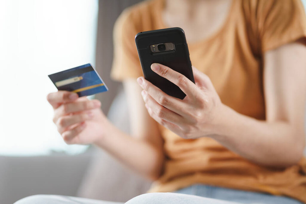 Mladá žena držící kreditní kartu a používající chytrý telefon pro online nakupování, internetové bankovnictví, e-commerce, utrácení peněz, práce z domova koncept - Fotografie, Obrázek