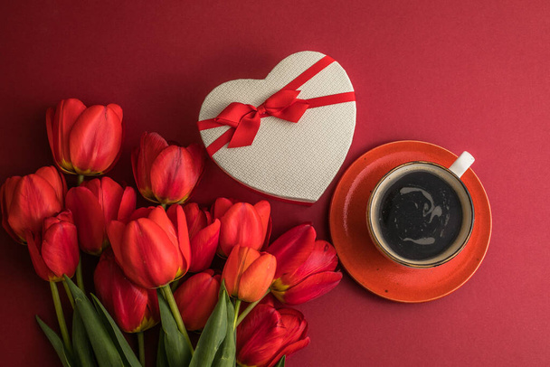 Ramo de tulipanes rojos y caja del corazón del regalo, arreglo de la taza de café con mucho espacio de copia para el texto. Concepto de humor de primavera. Tarjeta de felicitación para Cumpleaños, Dia de la Madre, Boda, San Valentín, Mujer. - Foto, imagen