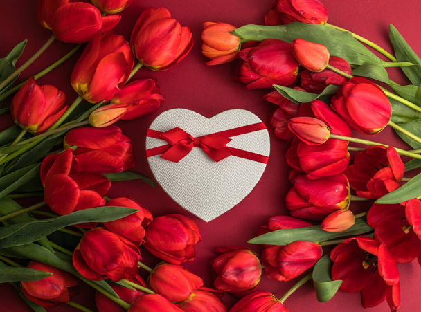 Bouquet of red  tulips and gift heart box, arrangement with a lot of copy space for text. Spring mood concept. Greeting card for Birthday, Woman, Mother's Day, Wedding, Valentines day. - Photo, Image