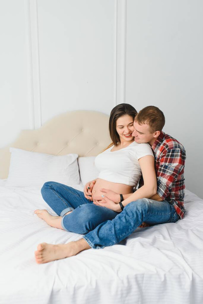 Young pregnant woman with husband on sofa in room - Valokuva, kuva