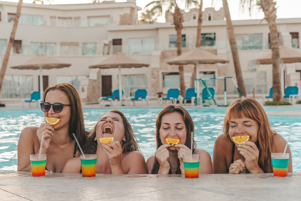 Группа красивых молодых женщин отдыхает в бассейне. Друзья отдыхают в бассейне и смеются в летний день - Фото, изображение