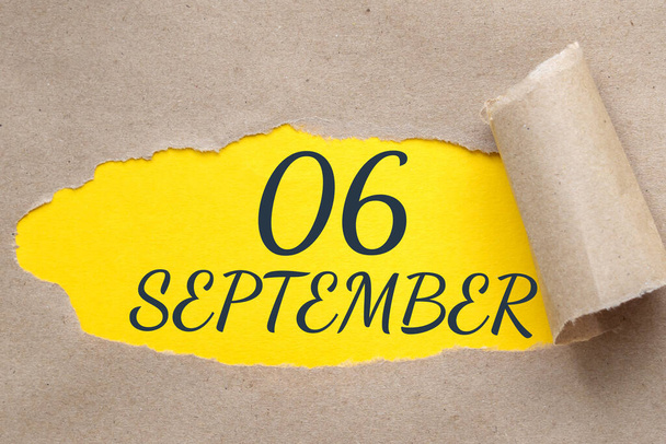 september 06. 06th day of the month, calendar date.Hole in paper with edges torn off. Yellow background is visible through ragged hole. Autumn month, day of the year concept. - Fotoğraf, Görsel