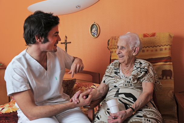 młody mężczyzna pielęgniarki i uśmiechający się starszy kobieta w jego sypialni - Zdjęcie, obraz