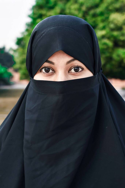 Primer plano de hermosa cara de mujer cubierta con hijab. Ojos brillantes perfectos de una chica musulmana. Niqab joven chica retrato con el fondo. - Foto, Imagen