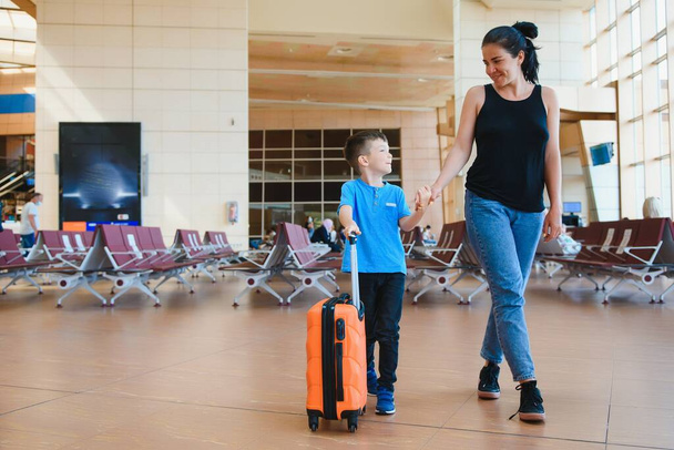 Mom with a little son and a suitcase at the airport. Travel concept - Фото, зображення
