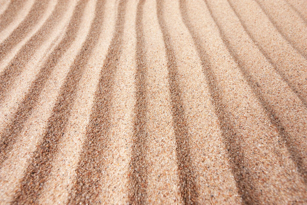 Yellow dry sand surface with grooves and wavy lines close-up perspective view with shallow depth of field nature background - 写真・画像