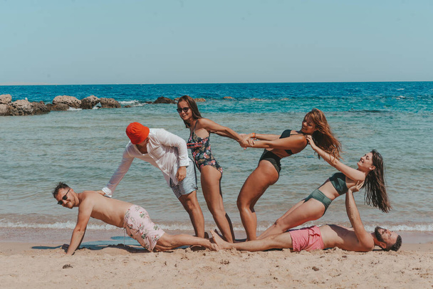 Χαρούμενη ομάδα φίλων που διασκεδάζουν στην παραλία. - Φωτογραφία, εικόνα