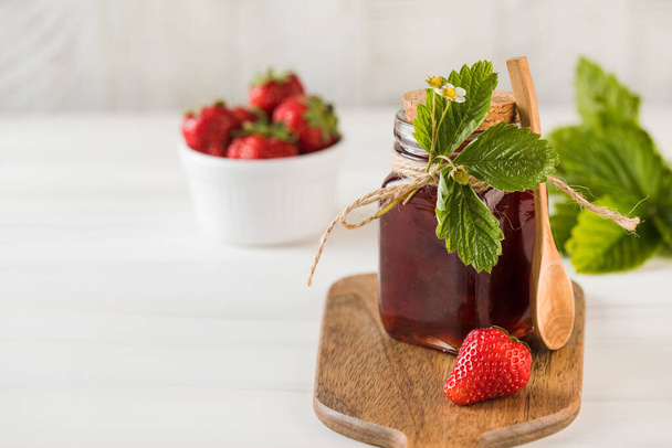 Strawberry jam in a jar on a wooden board. Fermented berries. Copy space. - Photo, image