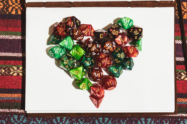 Nad głową obraz symbolu serca stworzonego z zielonym i czerwonym Role-playing gaming dice na szczycie otwartego notebooka w słońcu - Zdjęcie, obraz