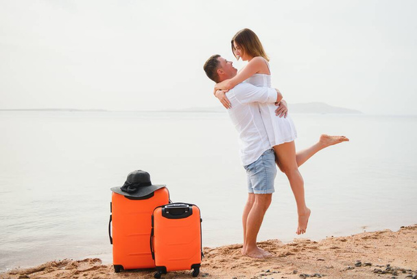 Young couple with suitcase on the beach in summer day. - Fotografie, Obrázek