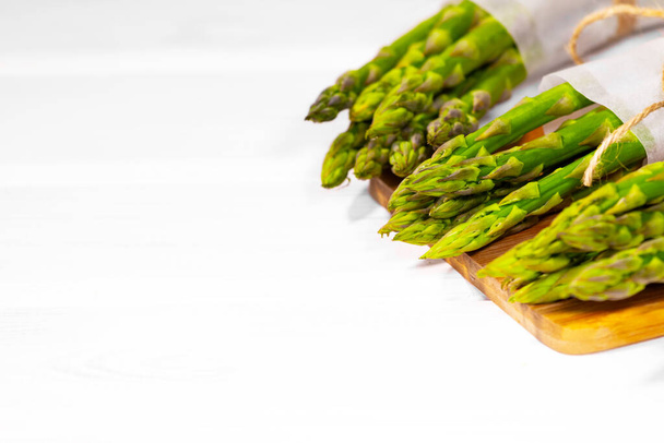Bando de espargos verdes frescos em mesa de madeira sobre fundo branco. Dieta vegetal saudável. Vegetarianismo. Papel de parede vegetal - Foto, Imagem