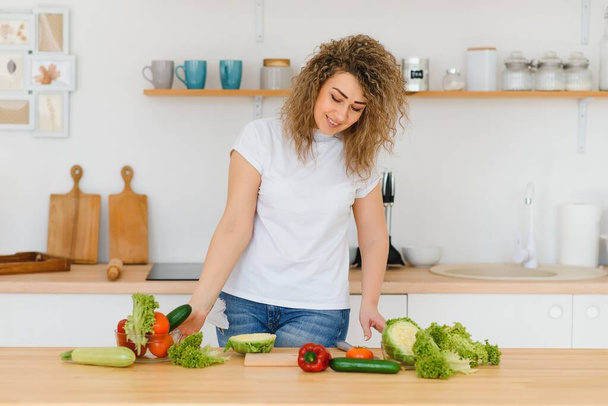 Happy young housewife mixing vegetable salad - Fotografie, Obrázek