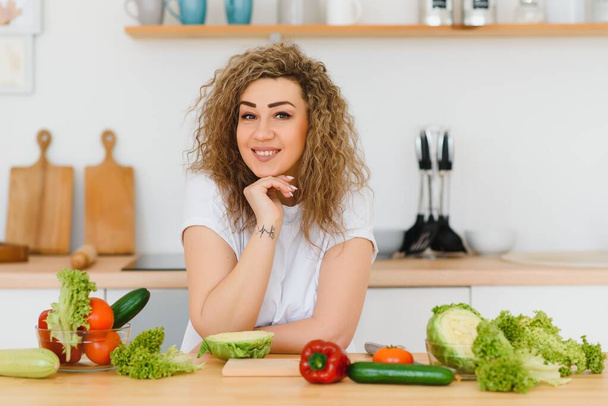 Happy young housewife mixing vegetable salad - Foto, Imagem
