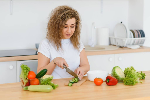 Young woman preparing vegetable salad in her kitchen. Healthy lifestyle concept beautiful woman with mixed vegetable. - Foto, Imagen