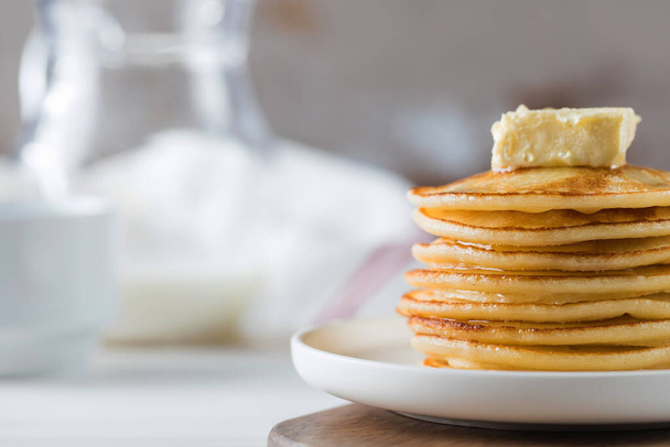 The pancakes are stacked in a plate with a piece of butter and drizzled with honey sauce. Breakfast concept. - Φωτογραφία, εικόνα