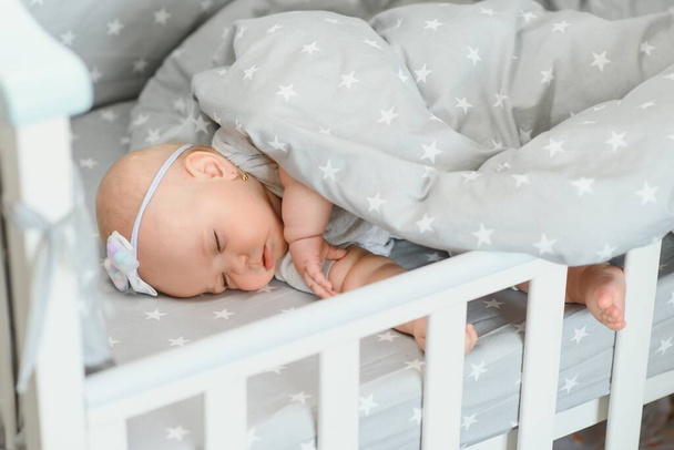 Adorable baby girl sleeping in the crib. Little child having a day nap in cot. Infant kid resting in nursery - Photo, Image