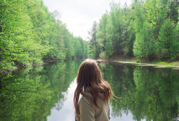 girl stands with his back to the camera. against the background of a beautiful river. green forest - Photo, Image