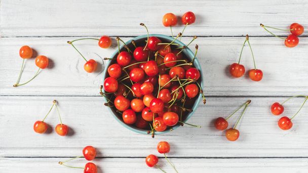 Fresh cherry in a bowl on a wooden white table - Foto, afbeelding